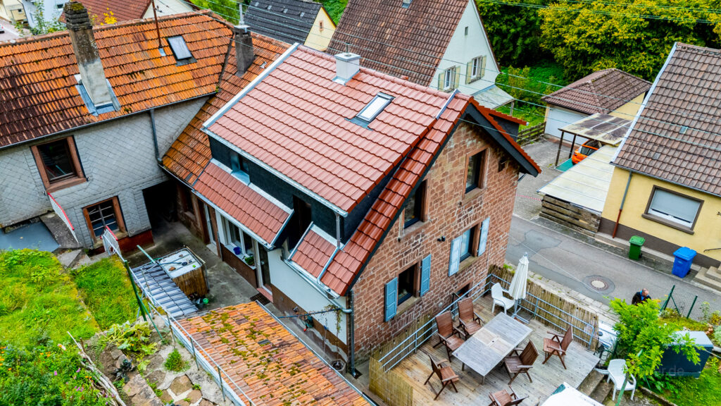 Ein traditioneles Haus wurde modern neu eingedeckt, die drohneneaufnahme zeigt das Huasdach auf der Rückseite
